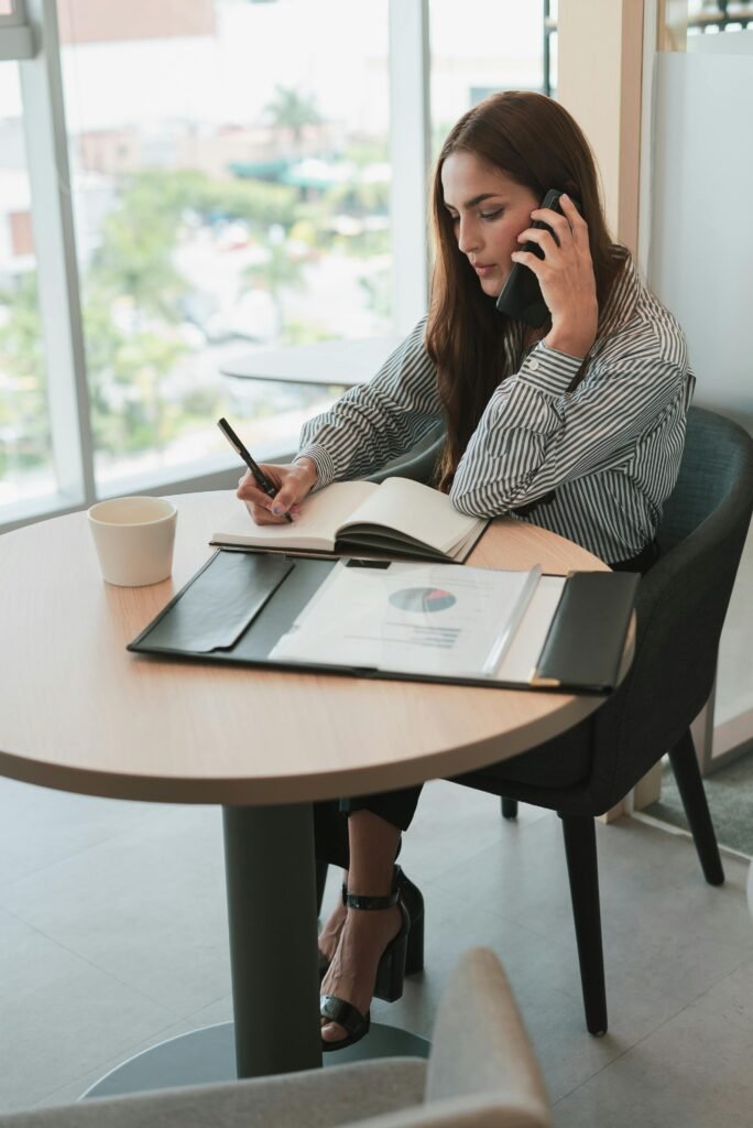 Sitting Woman Talking on Phone and Writing in Notebook